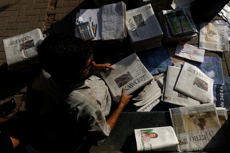 A hawker sorts out newspapers as he sells them along a street in Karachi, Pakistan October 7, 2018. Picture taken October 7, 2018. REUTERS/Akhtar Soomro