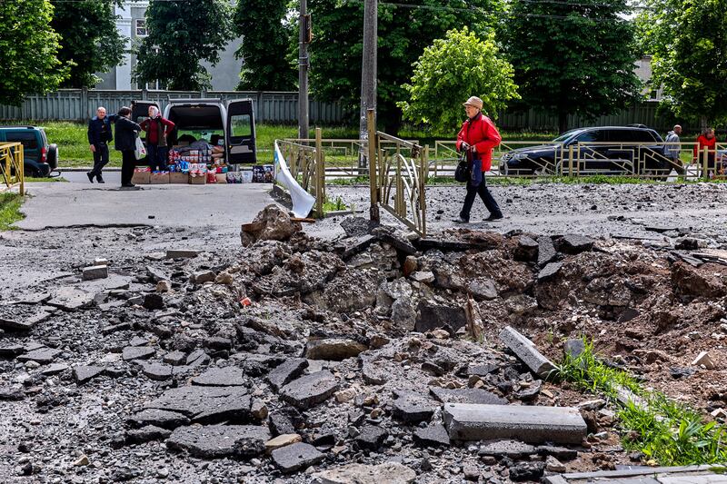 Locals walk past a road damaged by shelling in a residential area in Kharkiv. EPA