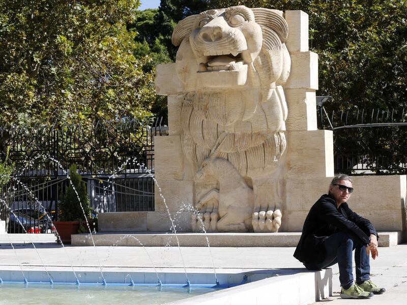 Polish archeologist Bartosz Markowski sits in front of the Lion of al-Lat, an ancient statue from the temple of the same name in Palmyra, during his visit to the national antiquities museum in the Syrian capital Damascus on October 28, 2018.  Syria reopened a wing of the capital's famed antiquities museum today after six years of closure to protect its exhibits from the civil war. / AFP / LOUAI BESHARA
