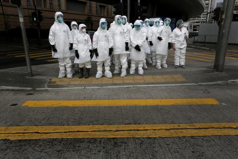 Health workers in protective gear wait on January 28, 2014, to enter a Hong Kong wholesale poultry market to do a cull. Authorities began culling 20,000 birds at the facility after poultry from southern mainland China tested positive for the H7N9 virus, the first time it had been found in imported poultry in Hong Kong. Vincent Yu/ AP photo