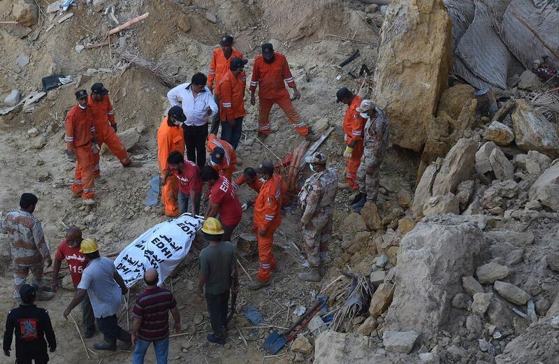 Pakistani rescuers move the body of a victim of a landslide in Karachi. Asif Hassan / AFP
