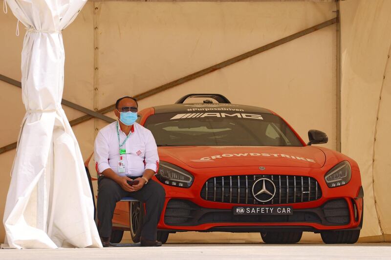 An attendant sits by a Mercedes AMG GT R, the official safety car for the 2021 F1 season, on the track prior to the F1 Grand Prix of Bahrain in Sakhir.  AFP