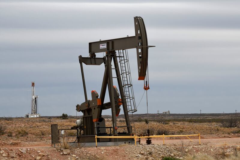 A pump jack operates in front of a drilling rig owned by Exxon near Carlsbad, New Mexico, U.S. February 11, 2019. Picture taken February 11, 2019. To match Insight USA-SHALE/MAJORS . REUTERS/Nick Oxford