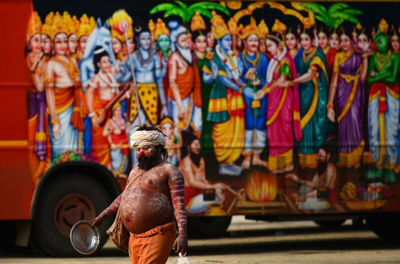A Hindu holy man walks past a vehicle bearing images of Indian Hindu deities in Allahabad.  Sanjay Kanojia / AFP