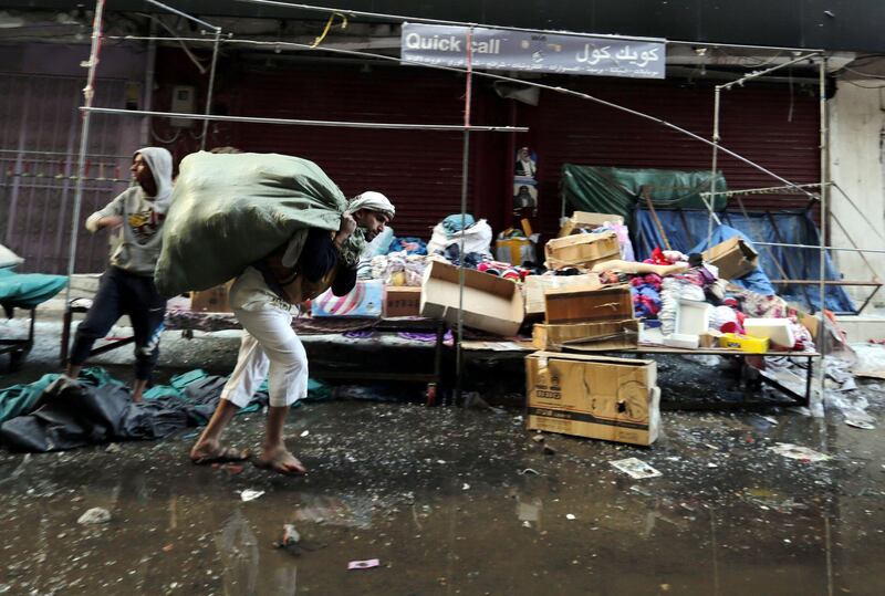 A Yemeni vendor carries belongings from a damaged mall near the residence of Yemeni ex-president Ali Abdullah Saleh. Yahya Ahrab / EPA
