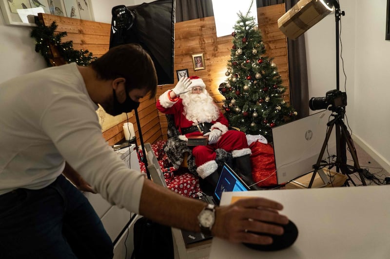 Aaron Spenedelow dressed as Santa Claus waves to the camera during a Zoom call with a family, as Santa's Grotto Live gets underway in Wembley, north London. AFP