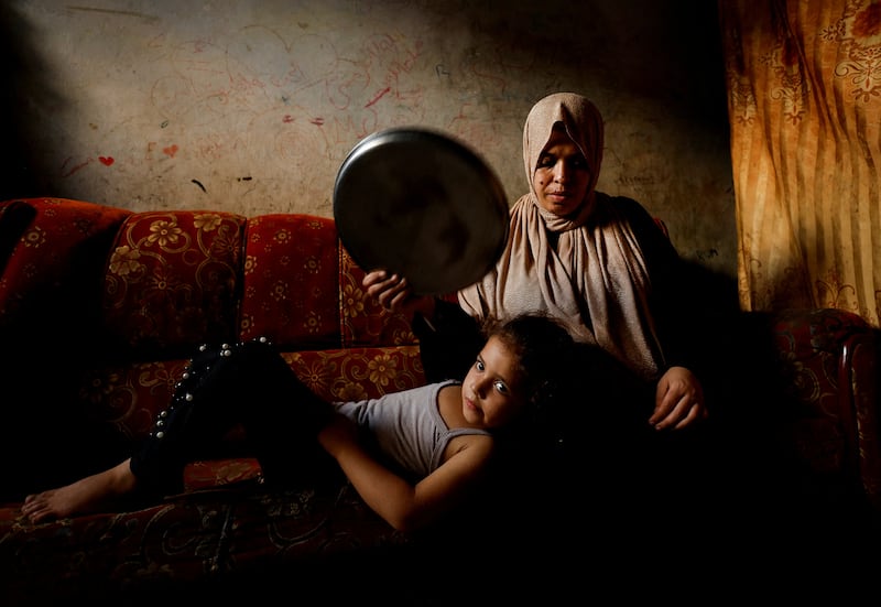 A Palestinian woman fans her daughter with a tray during a heatwave and lengthy power cuts in Gaza City. Reuters