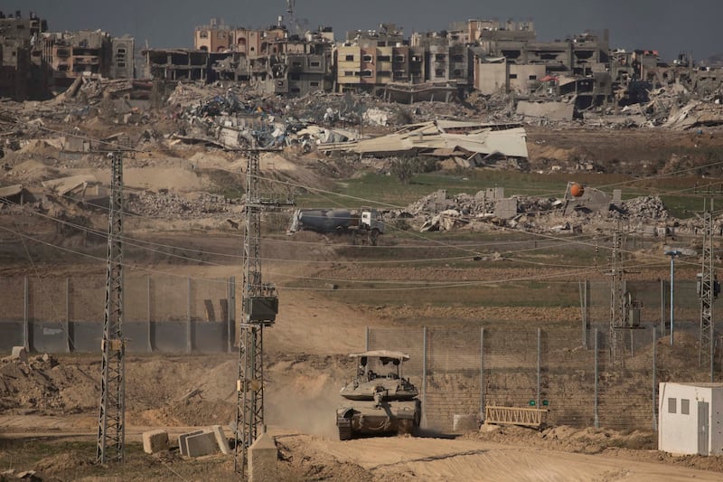 An Israeli tank moves along the border with Gaza against a backdrop of destroyed and damaged buildings. Getty Images