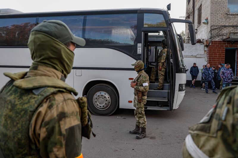Ukrainian separatist troops and Russian soldiers, rear right,  guard the buses with Ukrainian troops, in Mariupol.   EPA 