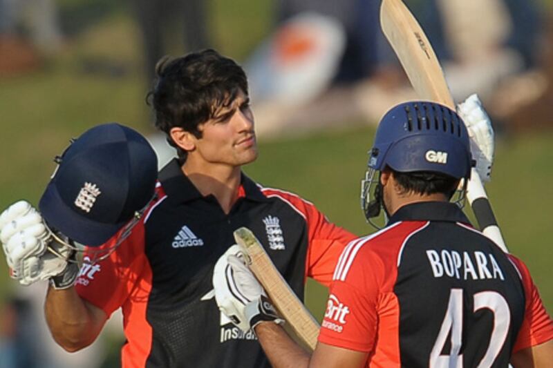 England's cricket captain Alastair Cook (L) raises his bat and helmet in celebration after scoring a century (100 runs) as as his teammate Ravi Bopara (R) looks on during the first One Day International (ODI) match between Pakistan and England at the Sheikh Zayed Stadium in Abu Dhabi on February 13, 2012. Cook won the toss and chose to bat in the first day-night international against Pakistan. AFP PHOTO/ LAKRUWAN WANNIARACHCHI

