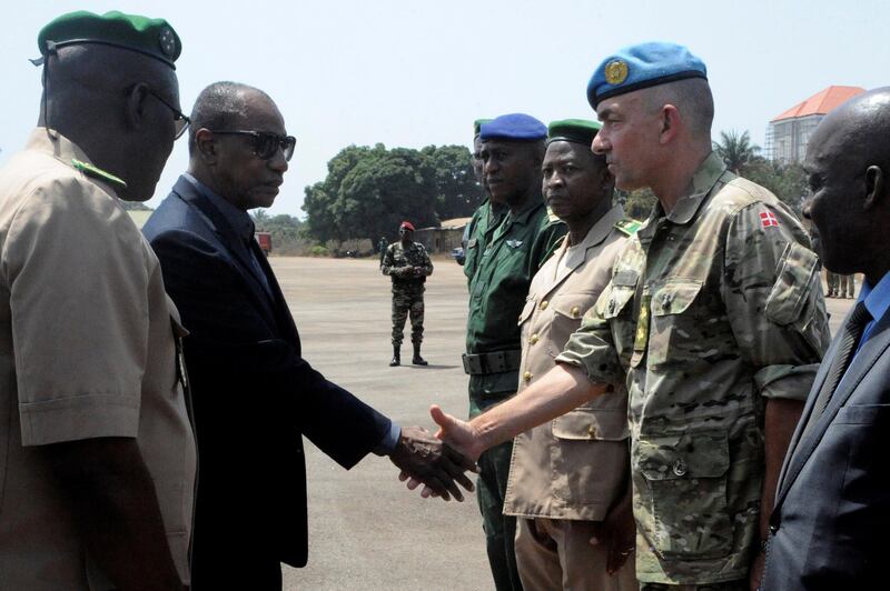 Guinea's President Alpha Conde (L) shakes hand with Head of the UN mission in Mali (Minusma) Danish commanding officer General Michael Lollesgaard (R) at the Conakry airport on February 17, 2016 during the repatriation of the bodies of UN peacekeepers killed in an Islamist attack on their base in Mali. - Seven peacekeepers were initially killed and at least 30 wounded in the early morning assault on the camp belonging to the UN force, known by the acronym MINUSMA, on February 12 in the northeastern town of Kidal. All seven killed were Guinean, three of them women, the source confirmed, representing the first female members of the mission killed in Mali. The MINUSMA mission, launched in July 2013, has been the most deadly for the UN since a deployment to Somalia during the civil war between 1993 and 1995. (Photo by CELLOU BINANI / AFP)