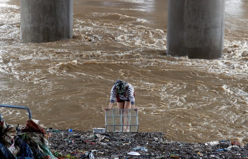 A woman cleans a glass cabinet near floodwaters in Marikina, Metro Manila. Reuters