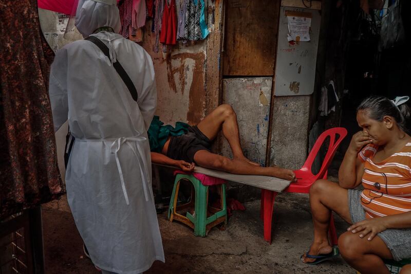A woman covers her nose as health workers enter an alley in Manila, Philippines. Four volunteer health workers were nicknamed 'Astronauts' by residents of Village 775, Zone 84 in Manila as they resemble such when donning their protective equipment. The healthcare volunteers conduct home visits twice a day to people infected or suspected to be infected with the novel SARS-CoV-2 coronavirus that causes the COVID-19 disease in one of the densely populated villages in Manila.  EPA