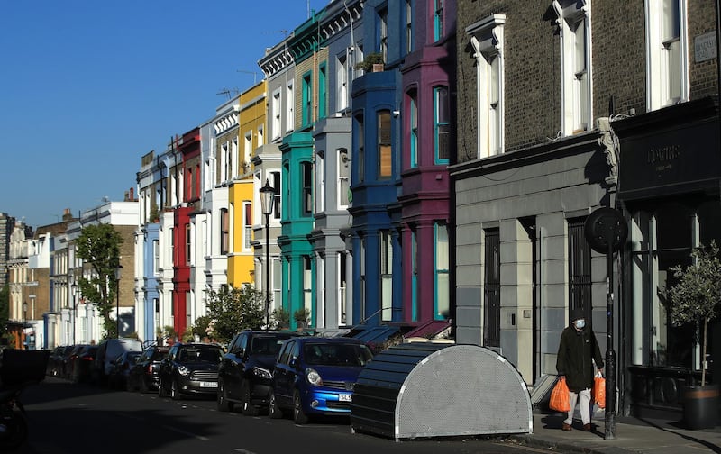LONDON, ENGLAND  - MAY 15: A person wearing face mask walks past the colourful houses of Notting Hill on May 15, 2020 in London, England. The prime minister announced the general contours of a phased exit from the current lockdown, adopted nearly two months ago in an effort curb the spread of Covid-19. (Photo by Andrew Redington/Getty Images)