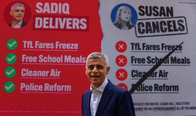 Mr Khan poses in front of his mayoral re-election campaign poster. Getty Images