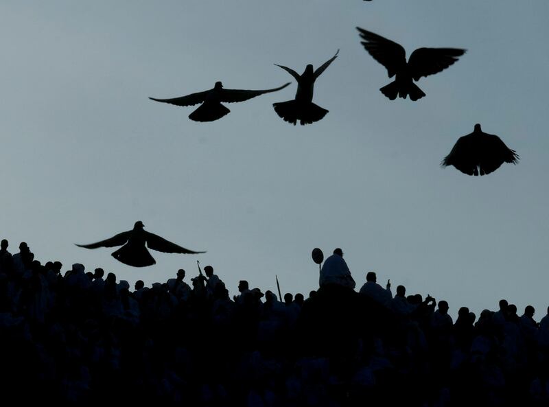 Pigeons fly as Muslim pilgrims pray on top of the rocky hill known as the Mountain of Mercy, on the Plain of Arafat, during the annual hajj pilgrimage, near the holy city of Mecca, Saudi Arabia.  One million pilgrims from across the globe amassed on Thursday in the holy city of Mecca in Saudi Arabia to perform the initial rites of the hajj, marking the largest Islamic pilgrimage since the coronavirus pandemic upended the annual event — a key pillar of Islam.  AP Photo