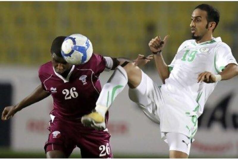Qatar’s Bilal Rajab, left, fights for the ball with Saudi Arabia’s Ahmad Abbass in their Group A Gulf Cup match in Aden last night. Saudi Arabia equalised in last minute to deny their opponents a semi-final spot.
