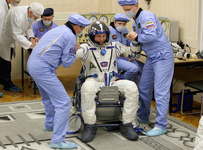 Russian Space Agency experts help Nick Hague to stand up after inspecting his space suit. AP Photo