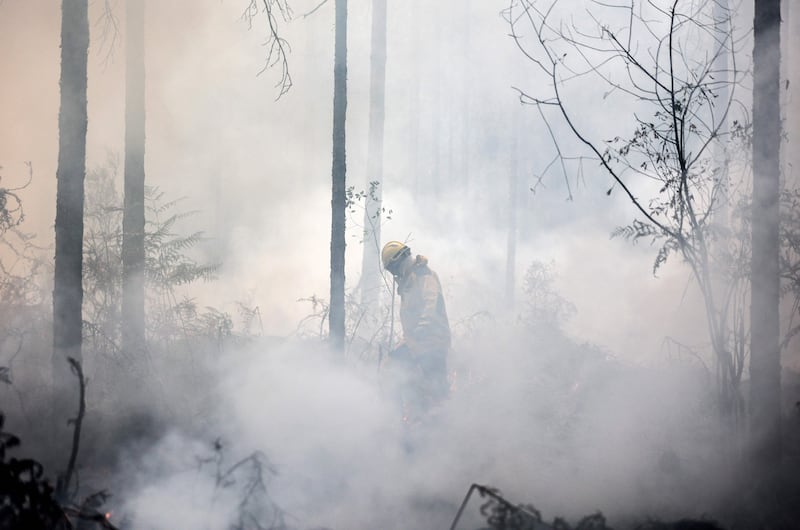 A French tactical firefighter lights a controlled fire to slow the advance of a wildfire near Belin-Belitet, south-western France. AFP