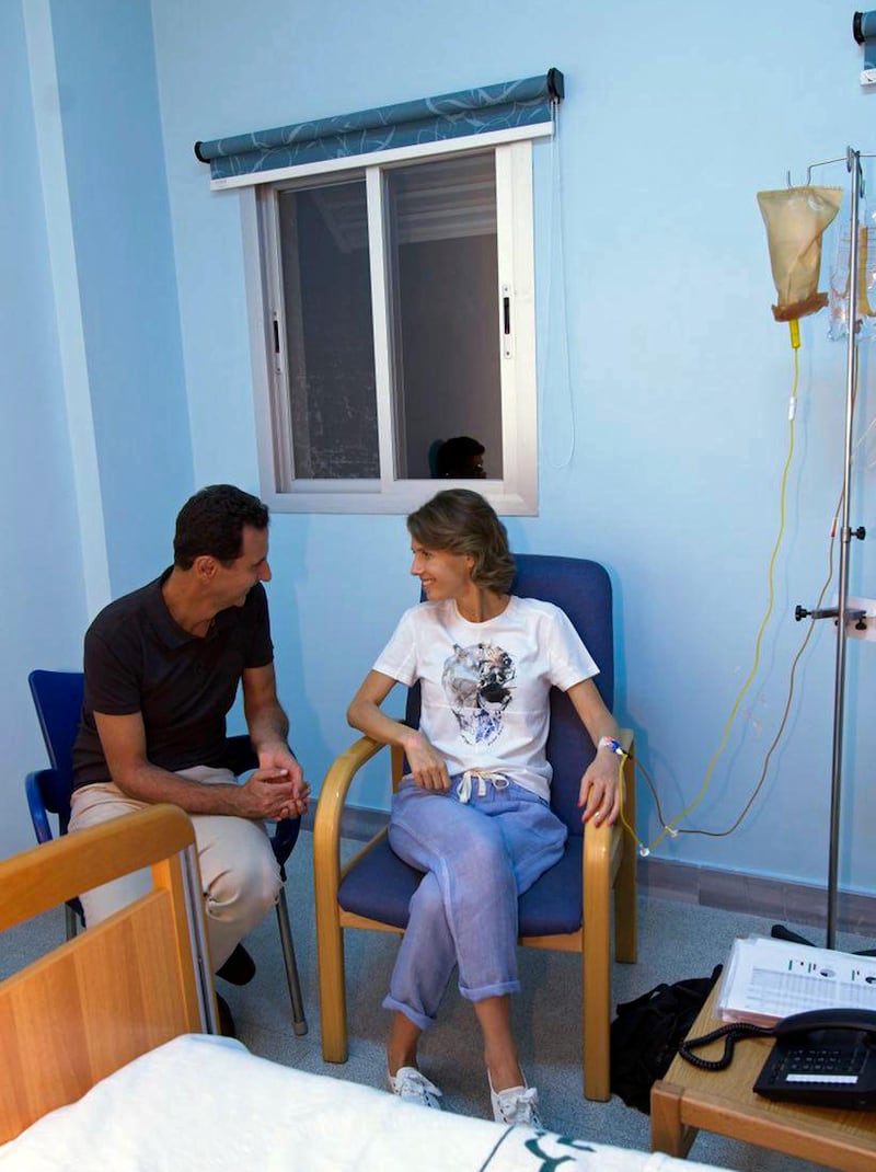 This photo posted Wednesday, Aug 8, 2018 on the official Facebook page of the Syrian Presidency, shows Syrian President Bashar Assad sitting next to his wife Asma Assad with an IV in her left arm in what appears to be a hospital room, in Syria. Syria's presidency said that the first lady has begun treatment for breast cancer. The statement said the "malignant tumor" was discovered in its early stages. Such announcements are uncommon in the Arab world. (Facebook page of the Syrian Presidency via AP)