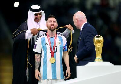 Sheikh Tamim bin Hamad Al Thani, Emir of Qatar, drapes the bisht over Lionel Messi's shoulders as Fifa president Gianni Infantino looks on. Reuters