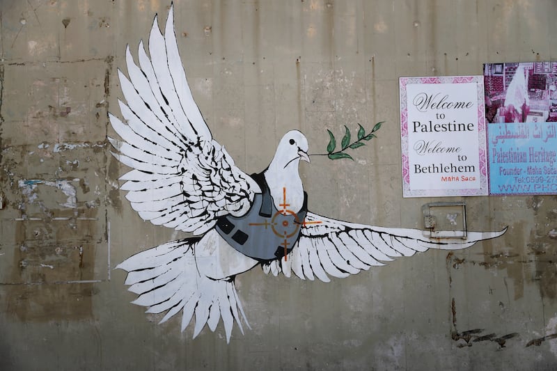 A graffiti by British street artist Banksy showing a dove with a bulletproof vest is seen in the Israeli occupied West Bank town of Bethlehem on March 15, 2017. AFP