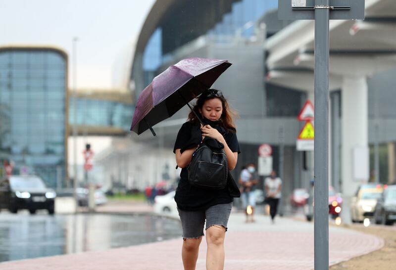 A pedestrian seeks shelter under an umbrella in Dubai. Another front of rain is forecast to arrive around 11pm on New Year's Eve, with Abu Dhabi set to experience several hours of rain