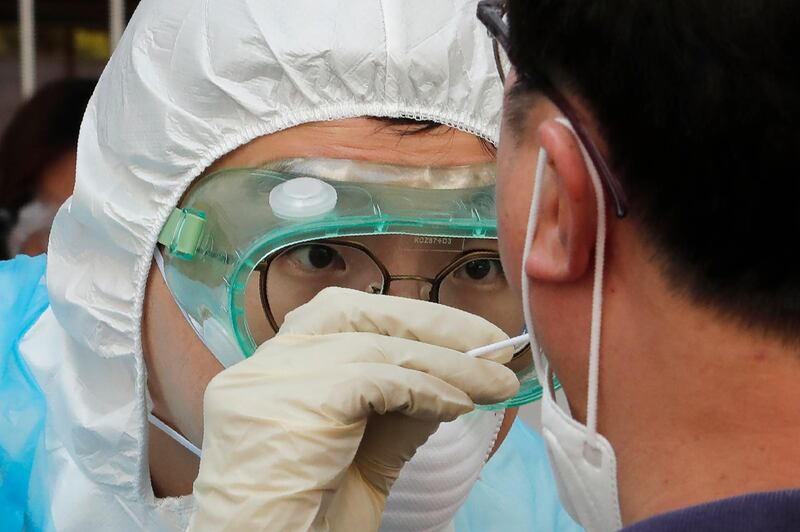 A medical staff wearing protective suits takes samples from a man during Covid-19 testing at a hospital in Seoul, South Korea. AP Photo