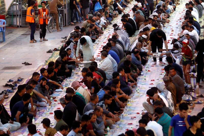 Men sit in rows awaiting the call of maghrib to break their fast in the Iraqi city of Najaf. Reuters