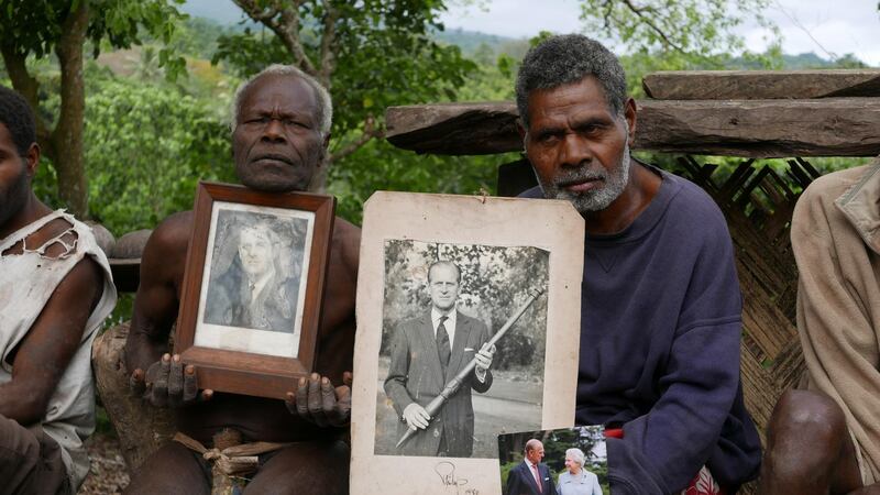 Village chief Jack Malia, right, from Tanna island holds pictures of Britain's Prince Philip and Queen Elizabeth II, next to other villagers in Younanen. Reuters