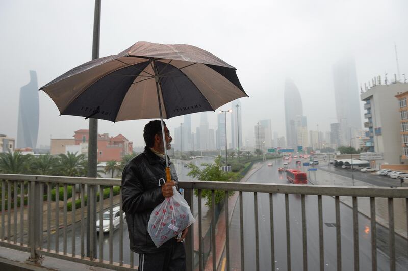 A man walks under an umbrella during rainfall in Kuwait City. EPA