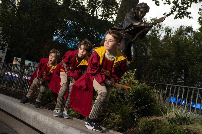 Harry Potter fans Sam Parker, Finn Bruce and Joey Bruce celebrate during the unveiling of the new Harry Potter statue at Leicester Square. Getty Images