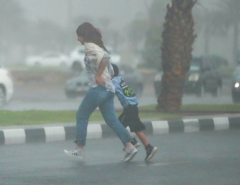 A woman and child dash for shelter from the rain in Sharjah. Victor Besa / The National