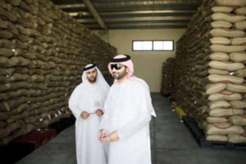 Rakan al Murar, right, a spokesman for Al Gharbia municipality, stands inside the rice distribution centre.