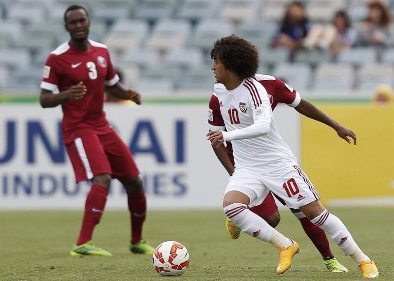 UAE football player Omar Abdulrahman, near, dribbles around Qatar defenders on Sunday in his side's 4-1 Asian Cup victory. Tim Wimborne / Reuters