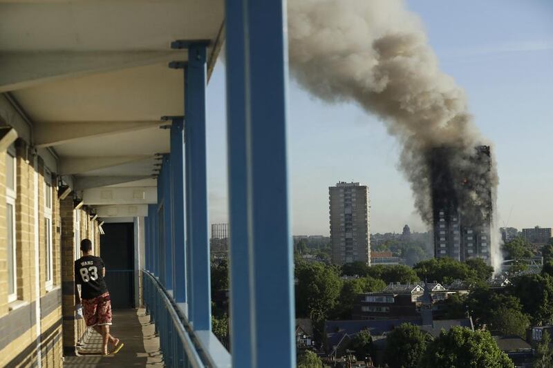 A resident in a nearby building watches smoke rise from a building on fire in London. At least 30 people were taken to hospitals, emergency officials said. Matt Dunham / AP Photo