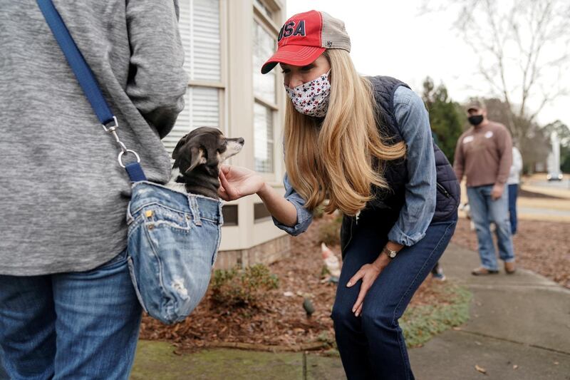 Republican US Senator Kelly Loeffler greets a voter's dog while speaking to them in front of their home in Loganville, Georgia.  Sen. Loeffler is locked in a right runoff with Democrat Raphael Warnock that could decide the balance of power in the US Senate. Reuters