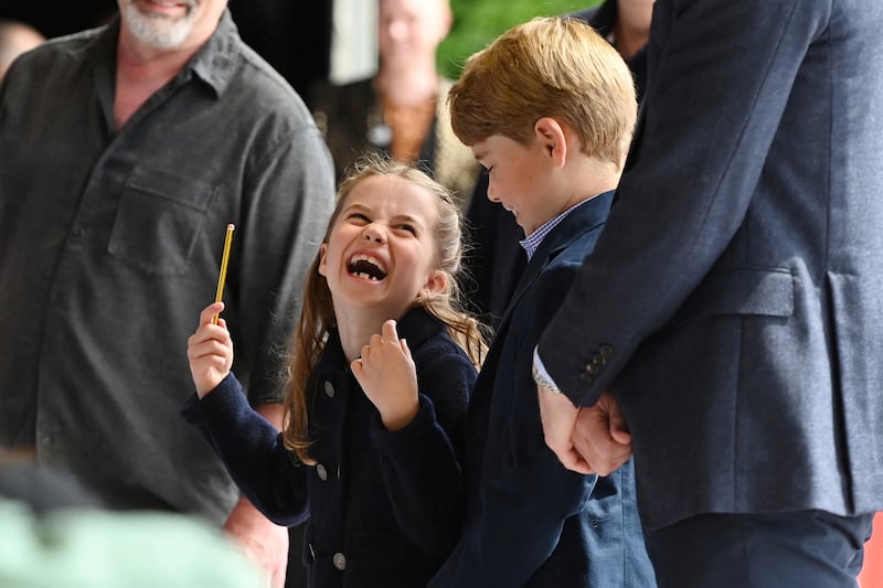 Princess Charlotte laughs as she conducts a band next to her brother Prince George during their visit to Cardiff Castle. Reuters