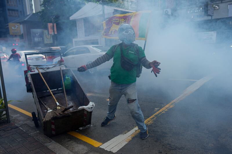 Protester throws a tear gas canister back at police officers during an anti-government protest march in Colombo, Sri Lanka. AP