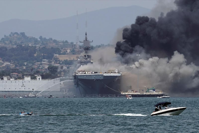 A recreational boat pulls a person on an inner tube on San Diego Bay as firefighting boats spray water on to 'USS Bonhomme Richard' as smoke rises from a fire on board the ship in San Diego, as seen from Coronado, California, US. Reuters