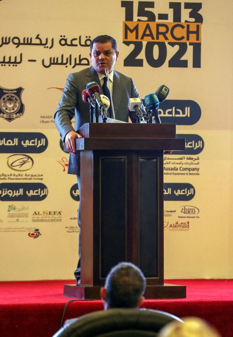 Libya's interim prime minister Abdul Hamid Dbeibah (L C) delivers a speech at a national conference on the COVID-19 pandemic, at a conference hall in the capital Tripoli, on March 13, 2021. / AFP / Mahmud TURKIA
