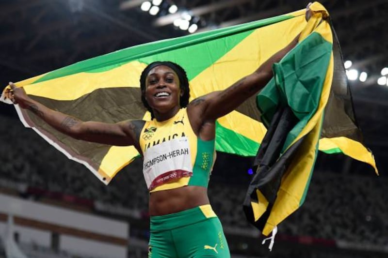 Jamaica's Elaine Thompson-Herah celebrates with the flag of Jamaica after winning the women's 200m final.