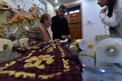 Iraqi priest Ammar Yaqo looks on as Karjiya Baqtar embroiders a precious prayer shawl using golden thread, to gift to Pope Francis during his upcoming visit to her Iraqi hometown Qaraqosh, in the Nineveh province, some 30 kilometres from Mosul, on March 4, 2021.  The two-metre shawl is entirely locally produced, from the checkered red and black fabric to the Syriac prayers hand-stitched along its edges in glimmering gold.
It was designed by Ammar Yaqo, the priest at the Al-Tahera Church in Qaraqosh. 
 / AFP / Zaid AL-OBEIDI
