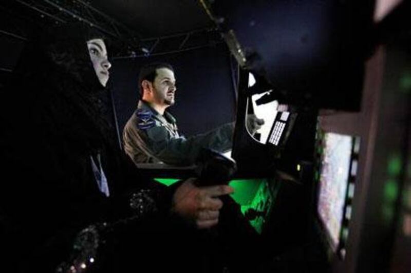 Ghazi Nemer Al Subaie, right, shows Raghda Musstsesm Zakaria how to fly the Euro Fighter during a flight simulation at Idex. Sammy Dallal / The National
