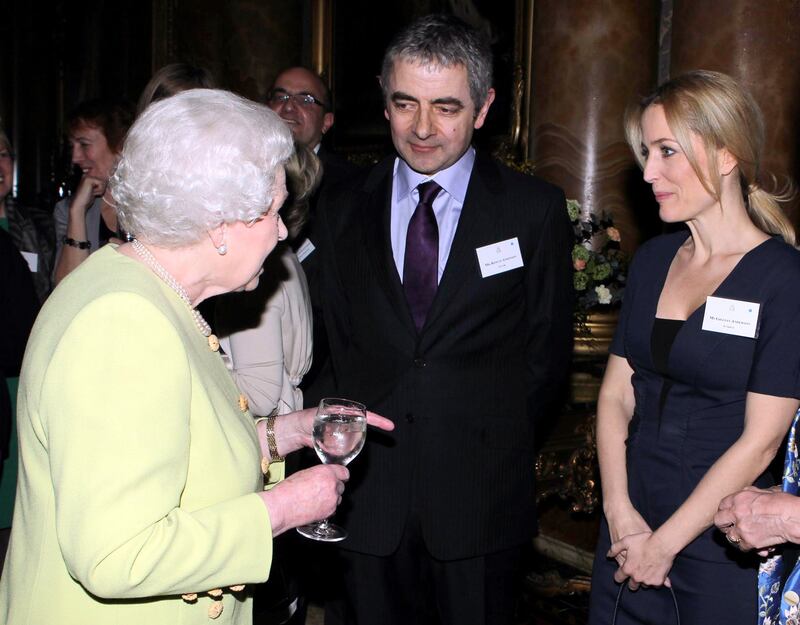 She meets actor Rowan Atkinson and actress Gillian Anderson at Buckingham Palace. Getty