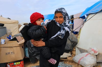 Displaced Syrians, from the eastern city of Deir Ezzor and Raqa who were forced to leave by the war against the Islamic State (IS) group, pose for a picture at the Ain Issa camp on December 18, 2017.  
As temperatures drop, tens of thousands of civilians forced out of their homes by Syria's war are spending yet another winter in flimsy plastic tents or abandoned half-finished buildings. And without heating, blankets and warm clothes, or access to proper medical care, even a simple cold can turn deadly. / AFP PHOTO / Delil souleiman