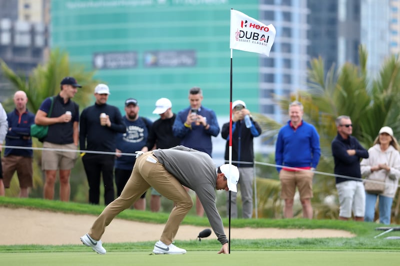 Rory McIlroy of Northern Ireland retrieves his ball after holing his second shot for an eagle on the 8th hole at Emirates Golf Club. Getty Images