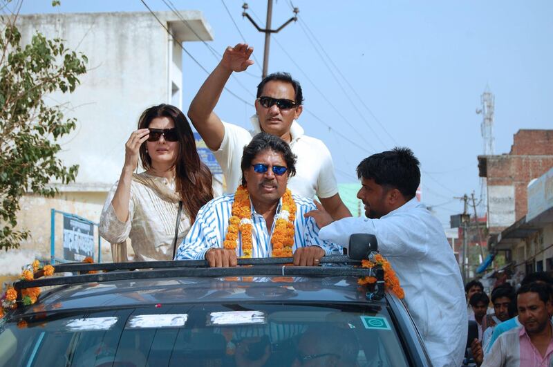 Former Indian cricketer Mohammad Azharuddin (REAR) is joined by his wife Sangeeta (L) and former teammate Kapil Dev (C) as he rides on a vehicle in Moradabad on May 5, 2009, as he campaigns for general elections.  Azharuddin who joined the ruling Congress party in February 2009, has been nominated to stand from the dusty north Indian town where he is drawing huge crowds.  Elections are being held across India with the final stages of voting finishing on May 13 and results expected on May 16.  AFP PHOTO/STR (Photo by STR / AFP)