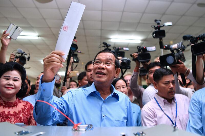 TOPSHOT - Cambodia's Prime Minister Hun Sen (C) prepares to cast his vote during the general election as his wife Bun Rany (L) looks on in Phnom Penh on July 29, 2018.
 Cambodia went to the polls early on July 29 in an election set to be easily won by strongman premier Hun Sen after the only credible opposition was dissolved last year, effectively turning the country into a one-party state.
 / AFP / Manan VATSYAYANA
