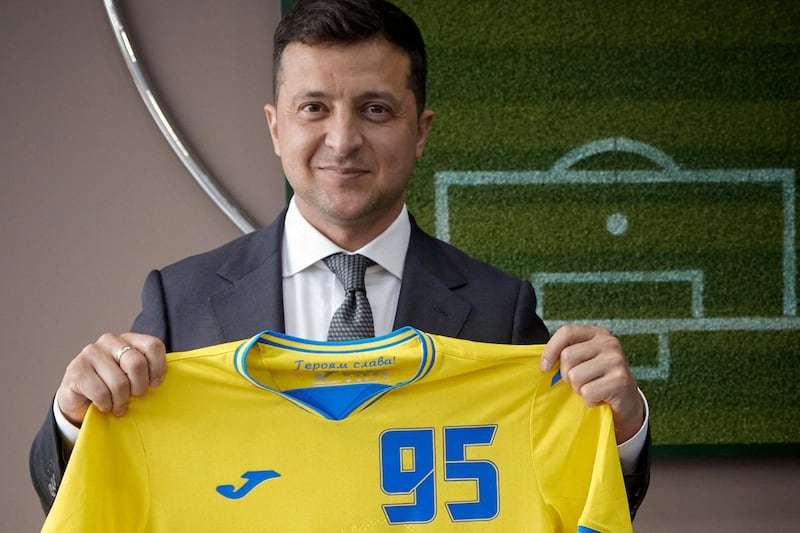 This handout picture taken and released by Ukraine's presidential press-service on June 9, 2021 in Kiev shows Ukrainian President Volodymyr Zelensky posing with a jersey of Ukraine's national football team. Ukraine insisted on June 7 it would not allow anyone to insult its football kit that features Moscow-annexed Crimea, while Western allies gave the uniforms emblazoned with popular patriotic chants a thumbs up. Kiev has provoked Moscow's ire after its football association unveiled UEFA EURO 2020 kits that show the outline of Ukraine including Crimea, which was annexed by Russia in 2014. - RESTRICTED TO EDITORIAL USE - MANDATORY CREDIT "AFP PHOTO / UKRAINE PRESIDENTIAL PRESS SERVICE" - NO MARKETING - NO ADVERTISING CAMPAIGNS - DISTRIBUTED AS A SERVICE TO CLIENTS
 / AFP / UKRAINE PRESIDENTIAL PRESS SERVICE / Handout / RESTRICTED TO EDITORIAL USE - MANDATORY CREDIT "AFP PHOTO / UKRAINE PRESIDENTIAL PRESS SERVICE" - NO MARKETING - NO ADVERTISING CAMPAIGNS - DISTRIBUTED AS A SERVICE TO CLIENTS
